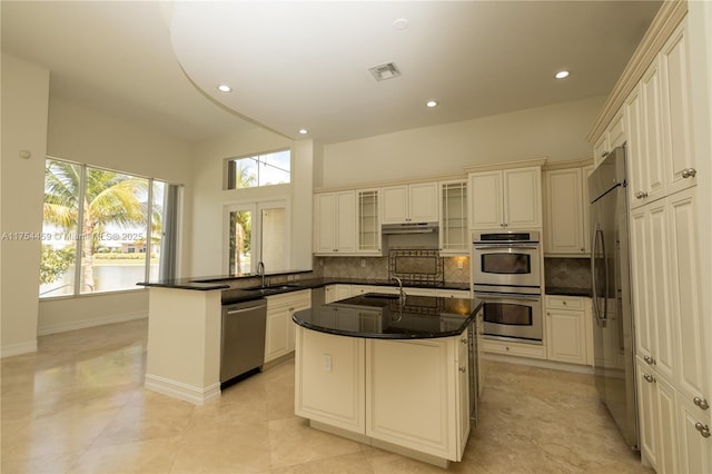 kitchen featuring tasteful backsplash, visible vents, appliances with stainless steel finishes, a peninsula, and a sink