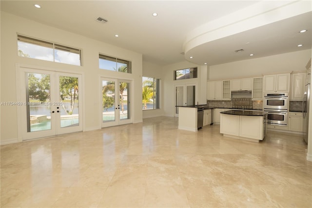 kitchen with french doors, tasteful backsplash, dark countertops, visible vents, and appliances with stainless steel finishes