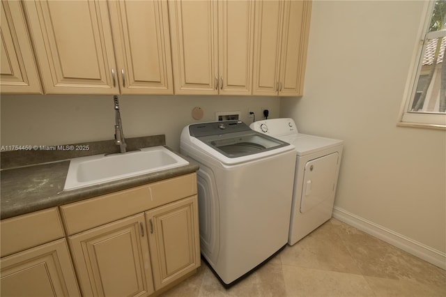 laundry area with washing machine and clothes dryer, cabinet space, light tile patterned flooring, a sink, and baseboards