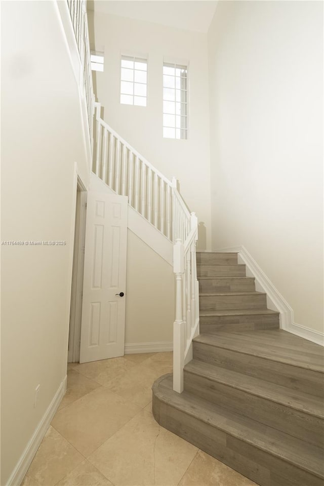 staircase with a high ceiling and baseboards