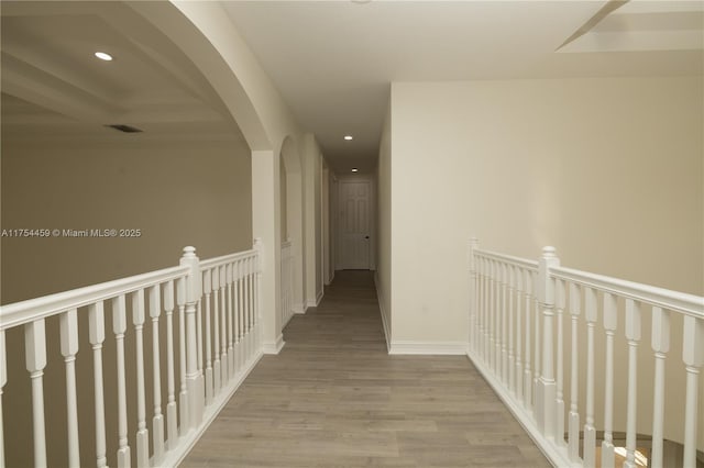 corridor with arched walkways, recessed lighting, visible vents, wood finished floors, and baseboards