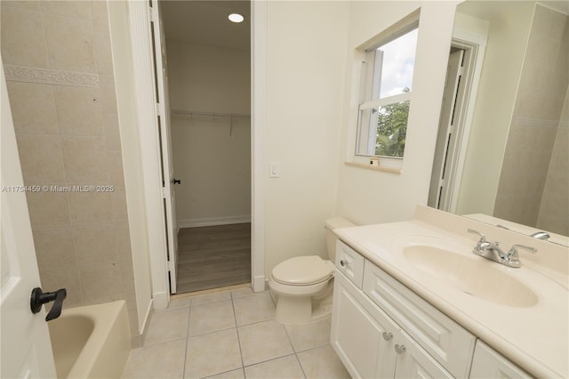 bathroom with toilet, vanity, baseboards, a spacious closet, and tile patterned floors