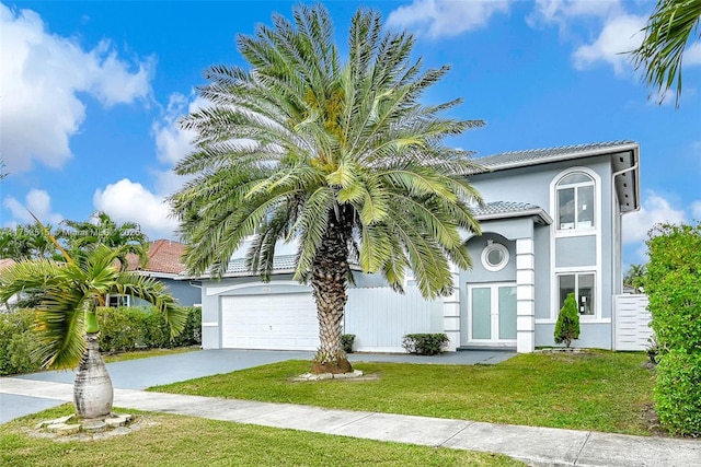 view of front of home with driveway, french doors, a tiled roof, stucco siding, and a front yard