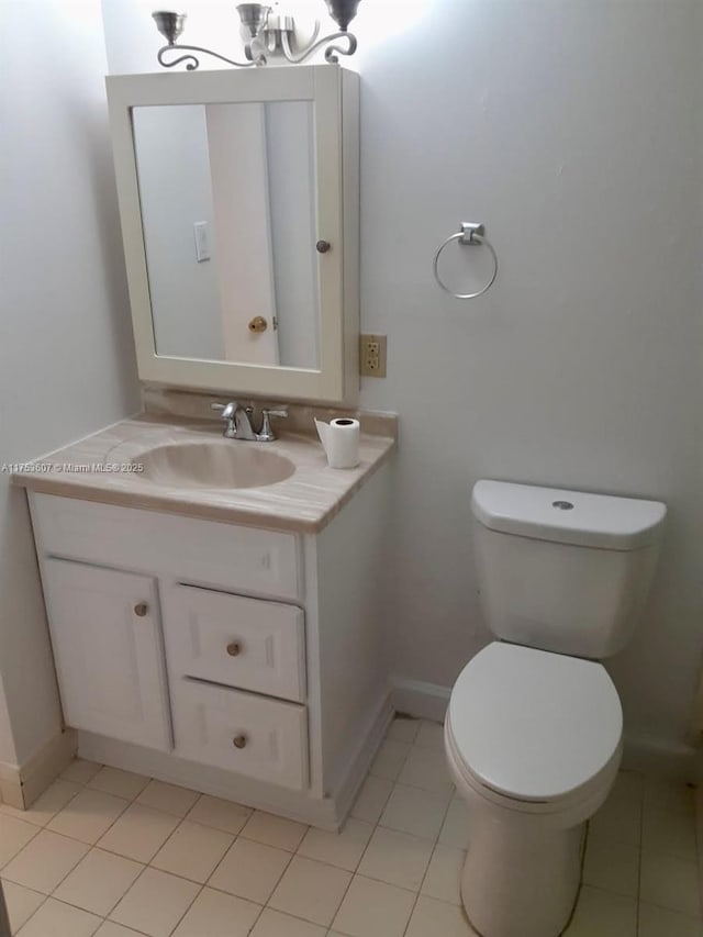 bathroom featuring toilet, an inviting chandelier, vanity, baseboards, and tile patterned floors