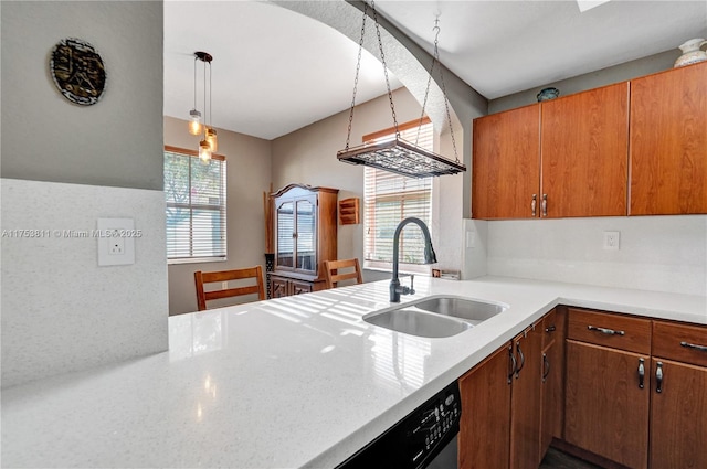 kitchen with decorative light fixtures, brown cabinetry, a sink, a peninsula, and dishwashing machine