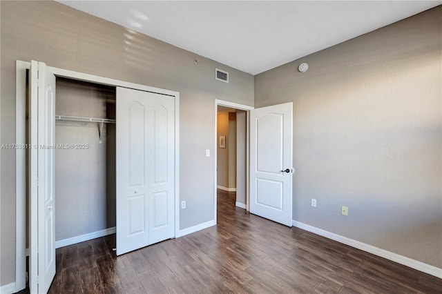 unfurnished bedroom with a closet, visible vents, baseboards, and wood finished floors