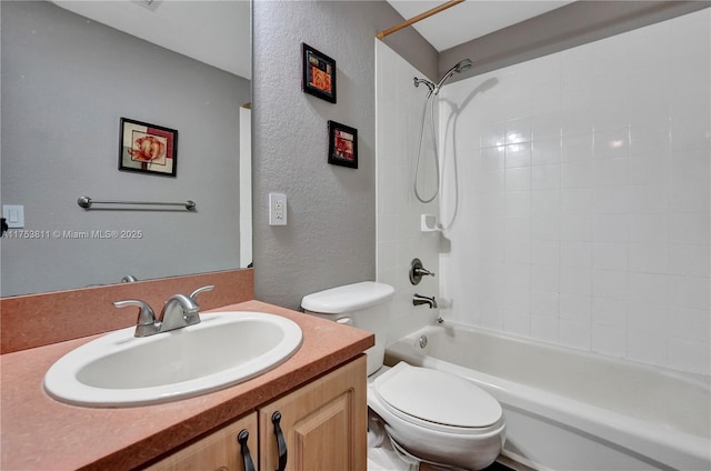 bathroom featuring a textured wall, vanity, toilet, and shower / bathtub combination