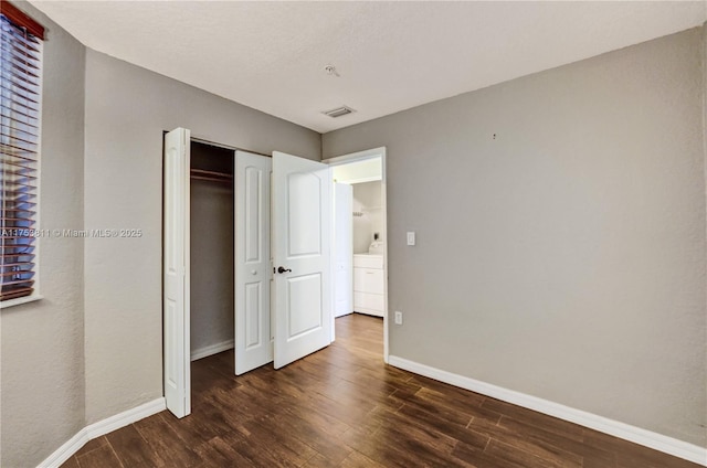 unfurnished bedroom with visible vents, baseboards, dark wood finished floors, and a closet