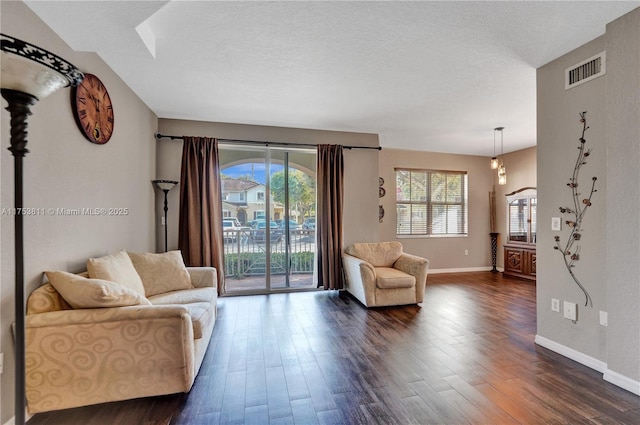 living room featuring a healthy amount of sunlight, visible vents, dark wood finished floors, and a textured ceiling