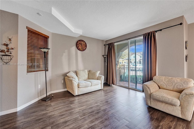 sitting room featuring dark wood-type flooring, a textured ceiling, and baseboards