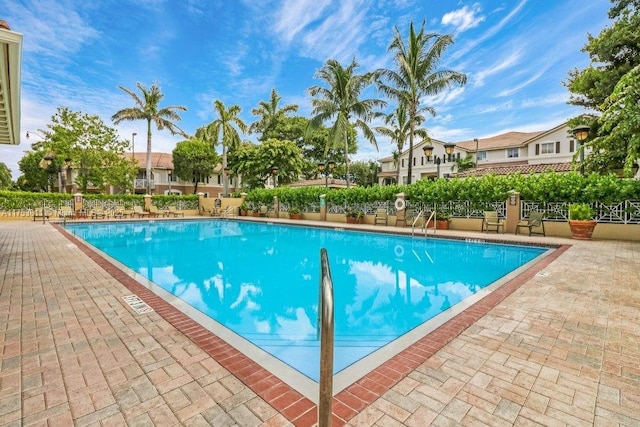 pool with a patio area and fence