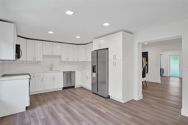 kitchen featuring light countertops, appliances with stainless steel finishes, light wood-style floors, white cabinets, and a sink