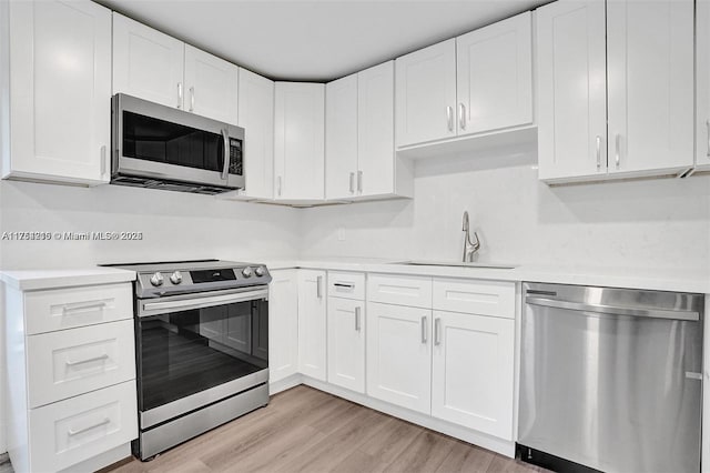 kitchen featuring stainless steel appliances, light wood-style flooring, a sink, and light countertops