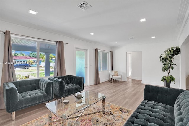 living room with light wood finished floors, visible vents, baseboards, crown molding, and recessed lighting