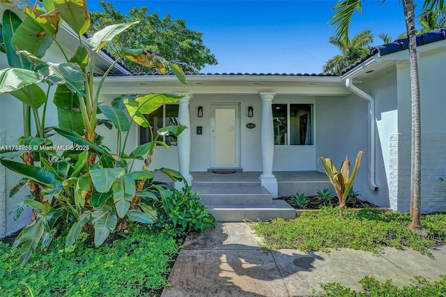 property entrance with covered porch and stucco siding