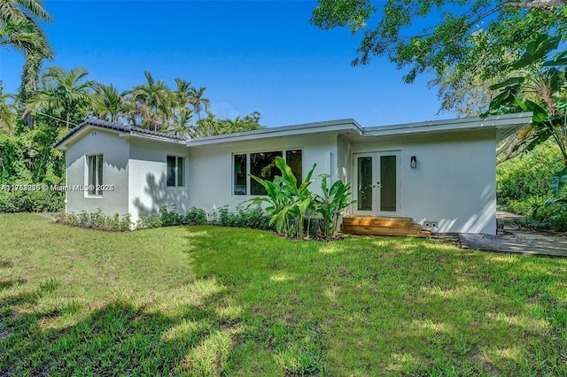 back of property featuring french doors, a lawn, and stucco siding