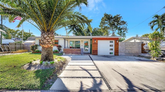 view of front of home featuring driveway, a garage, fence, and a front lawn