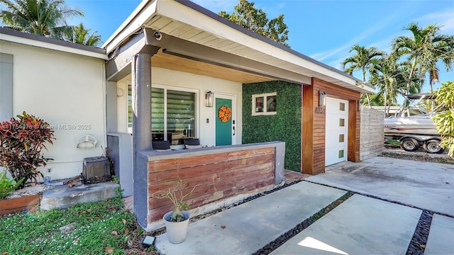 entrance to property featuring a garage, concrete driveway, and stucco siding