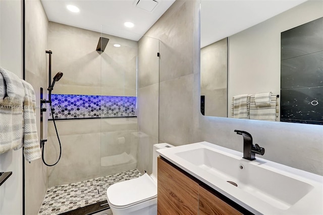 bathroom with tiled shower, vanity, toilet, and recessed lighting