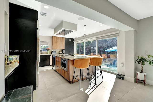 kitchen featuring visible vents, brown cabinetry, modern cabinets, oven, and wall chimney range hood