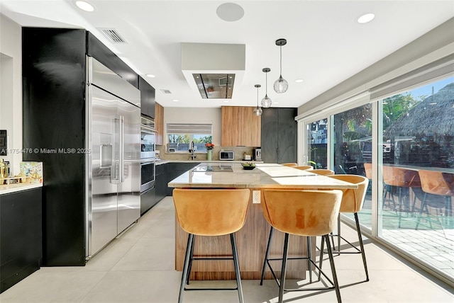 kitchen featuring visible vents, a kitchen island, modern cabinets, light countertops, and a kitchen bar