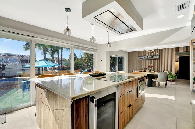 kitchen featuring black electric stovetop, beverage cooler, visible vents, stainless steel microwave, and modern cabinets