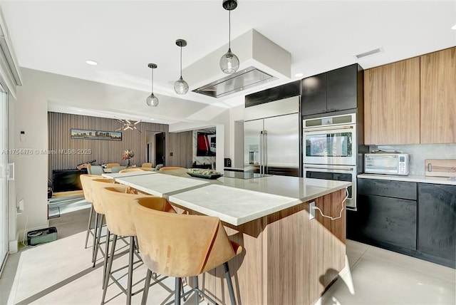 kitchen featuring visible vents, modern cabinets, appliances with stainless steel finishes, a breakfast bar, and light countertops