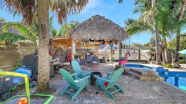 view of patio featuring an outdoor fire pit, a jacuzzi, fence, and a fenced in pool