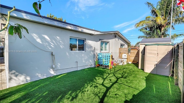 back of property featuring a yard, fence, and an outbuilding