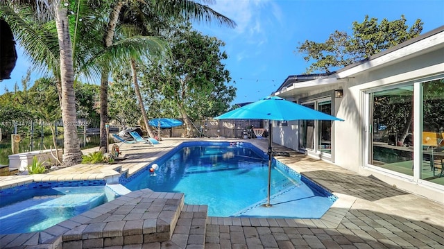 view of pool featuring a patio, a fenced backyard, and a pool with connected hot tub