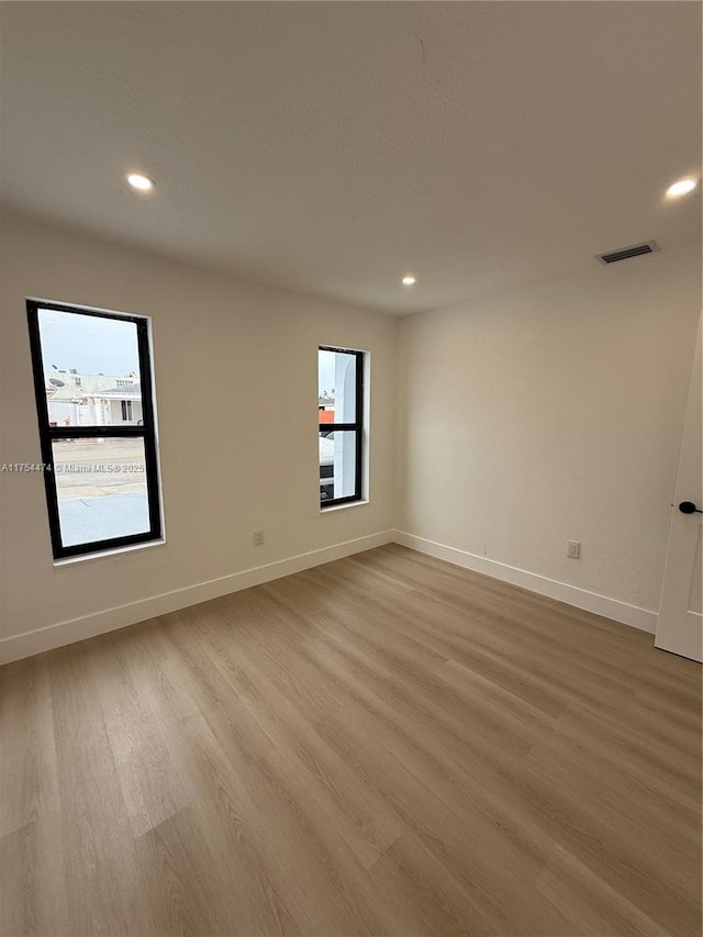unfurnished room with recessed lighting, baseboards, visible vents, and light wood finished floors