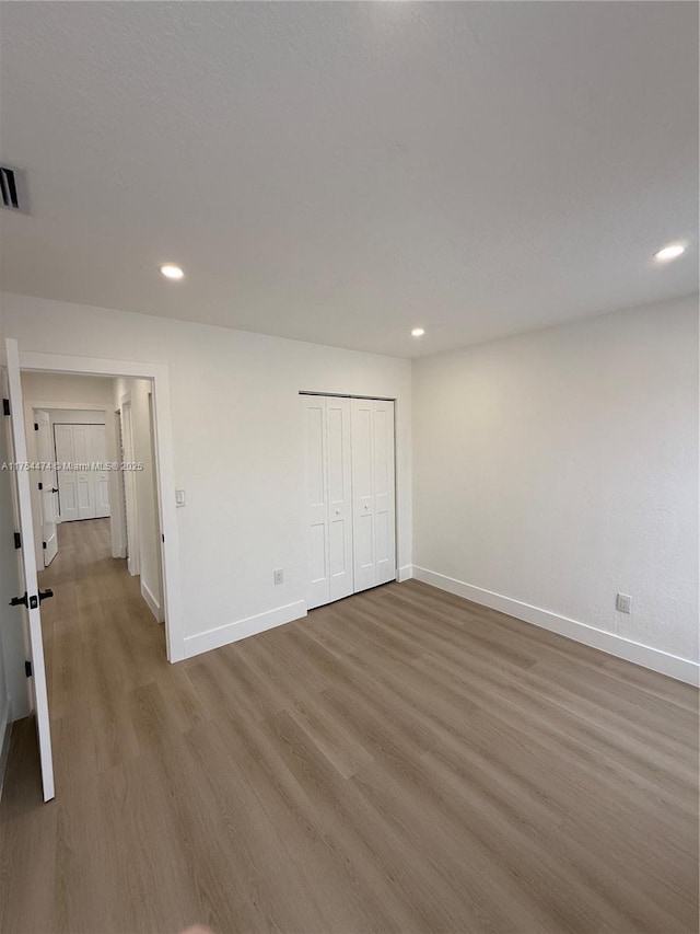 unfurnished bedroom with recessed lighting, a closet, visible vents, wood finished floors, and baseboards