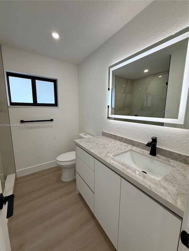 bathroom with a marble finish shower, a textured wall, toilet, a textured ceiling, and wood finished floors