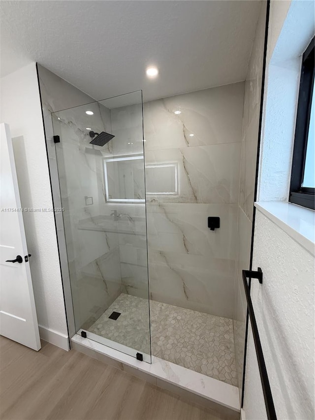full bathroom featuring a marble finish shower and wood finished floors