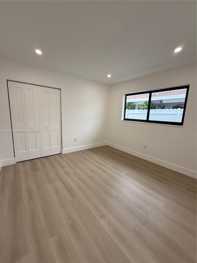 unfurnished bedroom with recessed lighting, light wood-style flooring, and baseboards