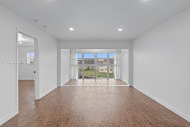 empty room with baseboards, wood finished floors, and a healthy amount of sunlight