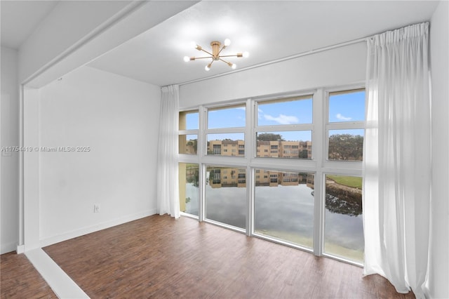 spare room featuring baseboards, a chandelier, and wood finished floors