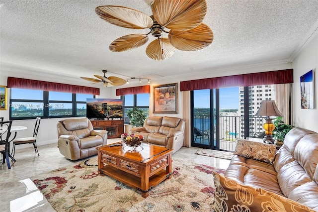 living room with a ceiling fan, ornamental molding, and a textured ceiling