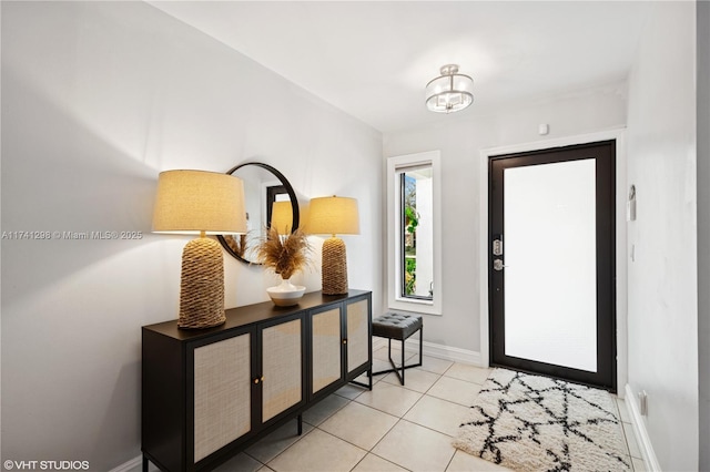 foyer entrance with an inviting chandelier, light tile patterned floors, and baseboards