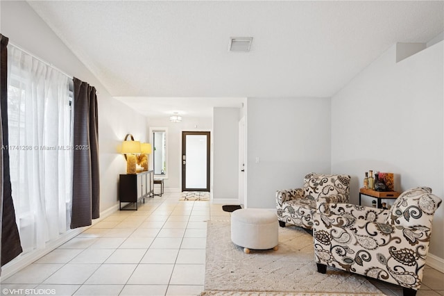 living area featuring light tile patterned floors, visible vents, and plenty of natural light