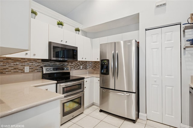 kitchen featuring light tile patterned floors, light countertops, white cabinets, appliances with stainless steel finishes, and backsplash