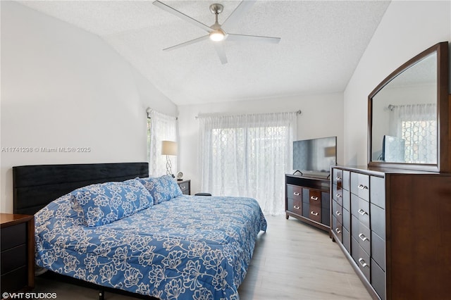 bedroom with lofted ceiling, a textured ceiling, wood finished floors, and a ceiling fan