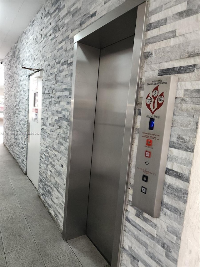 corridor with elevator and tile patterned floors