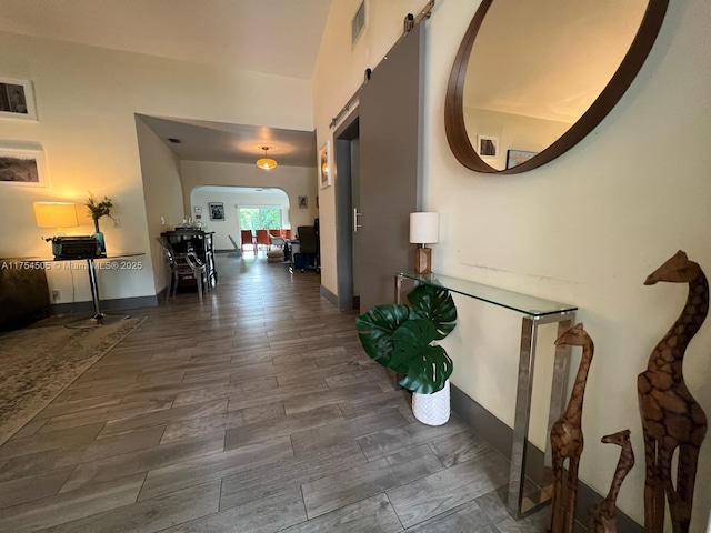 corridor with wood tiled floor, visible vents, arched walkways, and baseboards