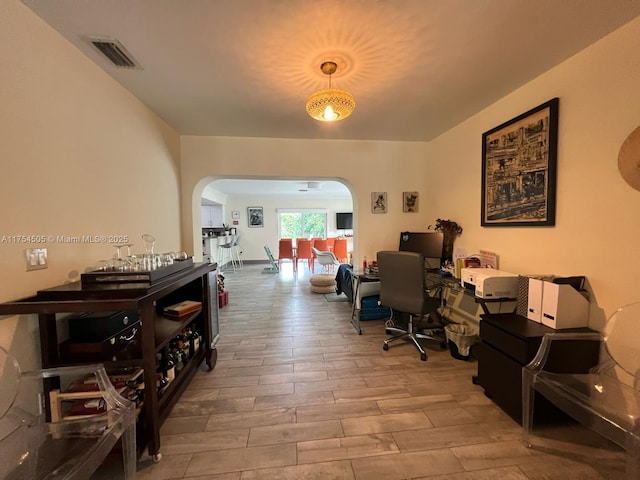 office featuring arched walkways, visible vents, and wood finished floors