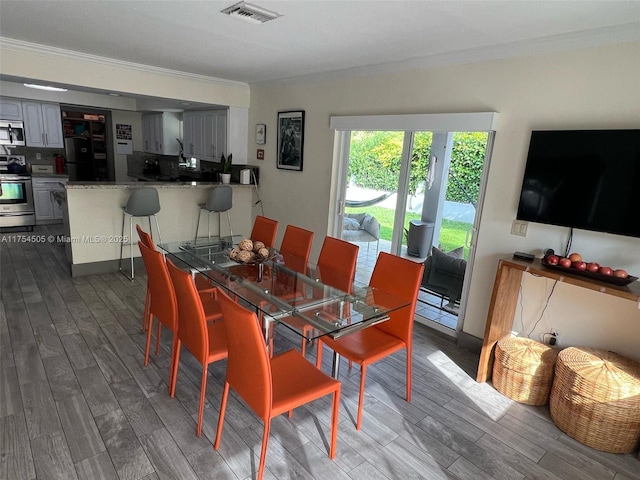 dining space with visible vents, dark wood finished floors, and ornamental molding