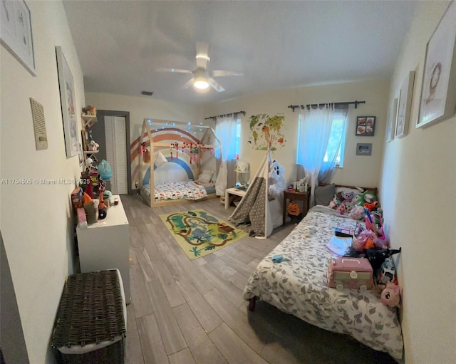 bedroom with a ceiling fan, visible vents, and wood finished floors