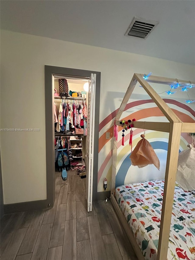 bedroom with visible vents, a walk in closet, a closet, and wood finish floors