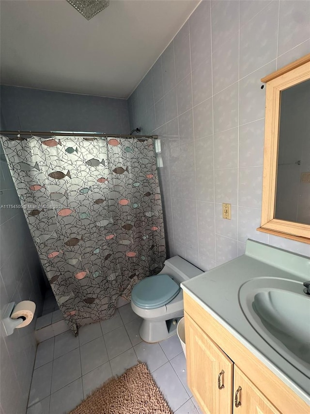 bathroom with tile walls, curtained shower, toilet, vanity, and tile patterned floors