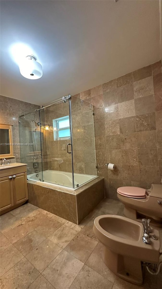 bathroom featuring toilet, tiled shower / bath, vanity, a bidet, and tile walls